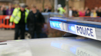 Police car with the police and members of the public in the background