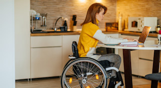 Woman sat in a wheelchair typing on a laptop